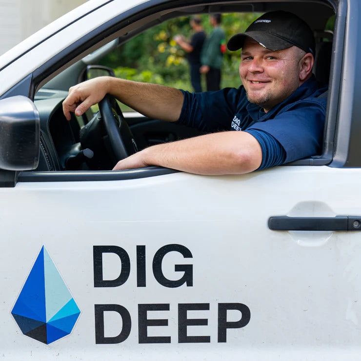 Smiling driver sitting in a Dig Deep truck, ready for a delivery